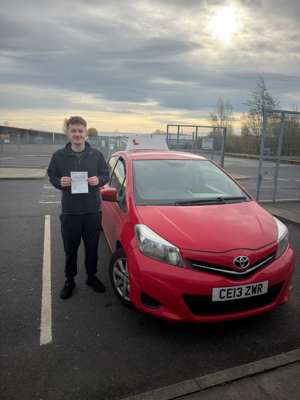 Student celebrating a driving test pass with learner car